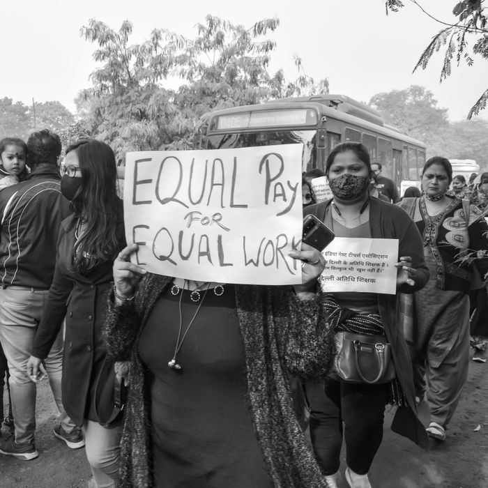 services-02 A group of people protesting for equal pay holding placards in a social justice demonstration.