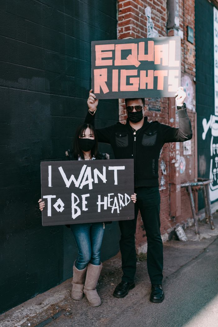 about-us Two protesters with placards advocating equal rights and being heard, standing together outside.